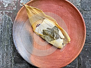 One Oaxacan tamale with hoja santa wrapped on the outside of the masa