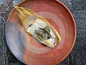 One Oaxacan tamale with hoja santa wrapped on the outside of the masa photo