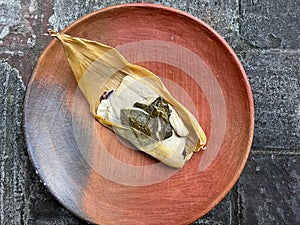 One Oaxacan tamale with hoja santa wrapped on the outside of the masa photo