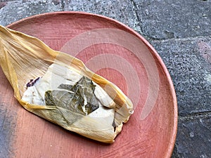 One Oaxacan tamale with hoja santa wrapped on the outside of the masa photo