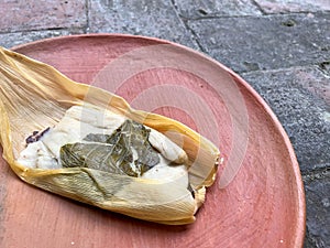 One Oaxacan tamales with hoja santa wrapped on the outside of the masa