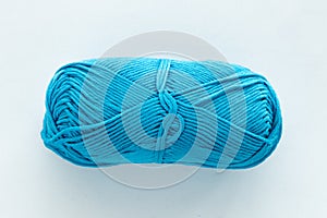 One oblong ball of blue in the center of the frame on a white woven background on the theme of handmade hobby knitting