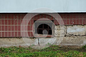 One old basement window with a rusty bars on the brown wall