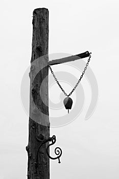 One old bell used at the farm mounted on a wood tree pillar - Black and White