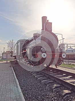 one old black iron steam locomotive with a green wagon stands on the rails of the railway