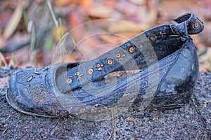 one old dirty black leather sandal shoe stands on the gray ground