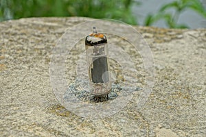 One old glass transistor lamp stands on a gray stone