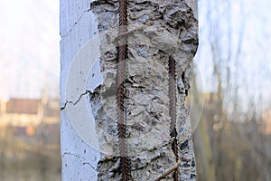 One old a gray concrete broken pillar with rusty brown reinforcement rods