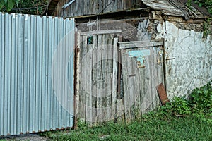 One old gray wooden rural door on a metal fence