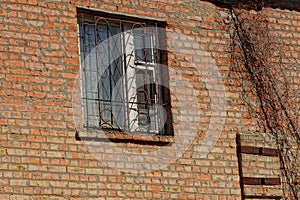 Old window with iron bars on a brown brick wall