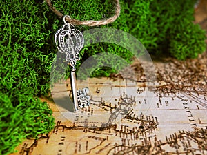 One old key lies on the moss on the background of an old map, the key to treasure, travel and adventure