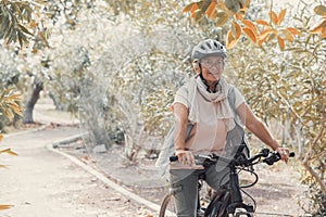 One old mature woman riding a bike and enjoying nature outdoors having fun. Senior having a healthy and fit lifestyle