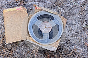 one old plastic magnetic reel for a tape recorder lies in a brown paper package