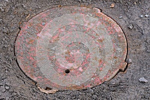 One old red rusty sewer hatch on the road