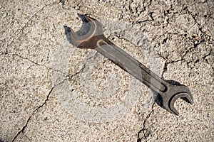 One old rusty wrench on a cement cracked background