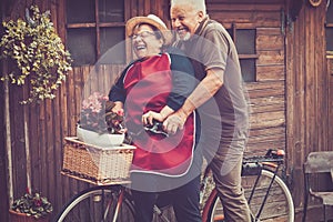 One old senior couple have fun together playing and joking outdoor on a bike. Active mature man and woman aging youthfully with photo