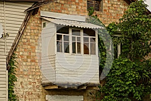 One old white covered wooden balcony on the brown brick wall