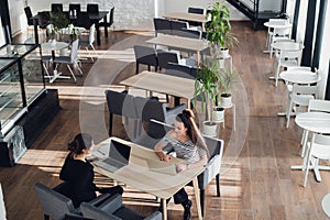 One-on-one meeting.Two young business women sitting at table in cafe. Girl shows colleague information on laptop screen