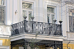 One open black iron balcony with a wrought pattern on a white concrete wall