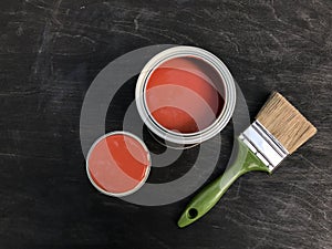 One open can with beautiful red paint on a black matte wooden background.