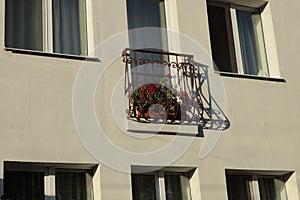 One open iron brown balcony with flowerpots and red flowers