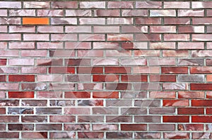 One orange-colored brick stands out from the other bricks that make up the wall fragment