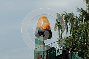 One orange warning light on a green iron fence