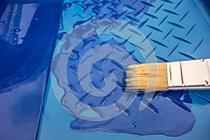 One paint brush on a blue plastic tray with blue paint