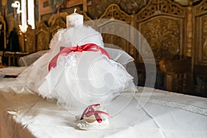 One pair of White bootees and big white candle for baby baptism party shower with red ribbon photo