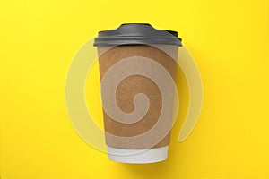 One paper cup on yellow background, top view. Coffee to go