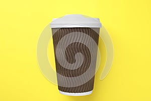 One paper cup on yellow background, top view. Coffee to go