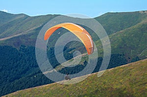 One paraglider flies over a mountain valley in summer sunny day in the Carpathians in Ukraine.