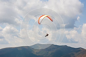 One paraglider fly over a mountain valley on a sunny summer day.