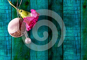 One pearl necklace with a pink carnations flower and a sea shell over green background. Vanetine`s gift concept