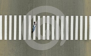 One pedestrian crossing zebra crosswalk, aerial, top view