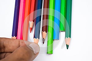 One person arranging some different colored wood pencil crayons on a white background