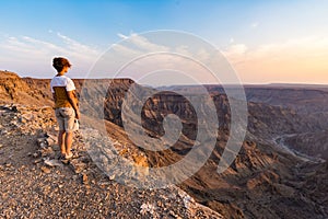 One person looking at the Fish River Canyon, scenic travel destination in Southern Namibia. Expansive view at sunset. Wanderlust t