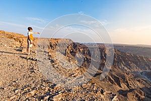 One person looking at the Fish River Canyon, scenic travel destination in Southern Namibia. Expansive view at sunset. Wanderlust t