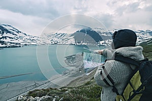 One person looking at trekking map, dramatic sky at dusk, lake and snowy mountains, nordic cold feeling