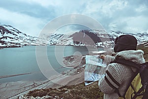 One person looking at trekking map, dramatic sky at dusk, lake and snowy mountains, nordic cold feeling