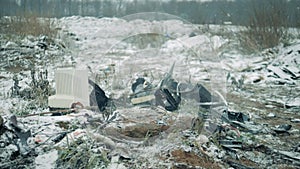 One person smashes old TV at a dump, using hammer.