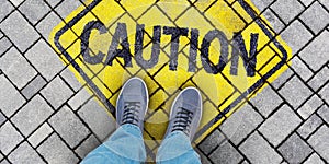 One person is standing on the street with caution sign on pavement