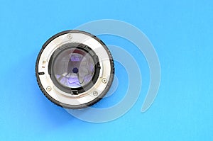 One photographic lense lie on a bright blue background. Space fo