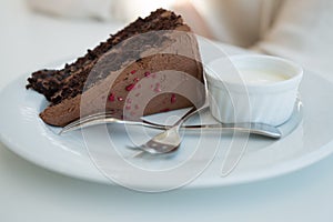 One piece of chocolate cake with two forks on white plate