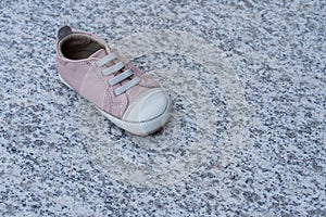 One pink baby shoe on a marble background. Concept of child abuse, kidnapping or pedophilia