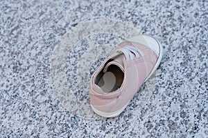 One pink baby shoe on a marble background. Concept of child abuse, kidnapping or pedophilia