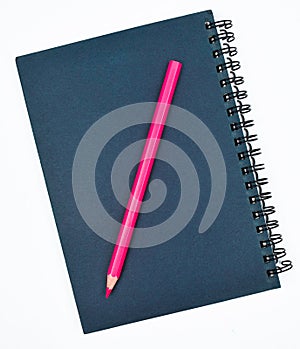 One pink colored wood pencil crayon placed on top of a blue paper diary