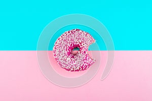 One pink donut on a mint and pink background