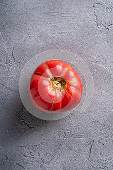 One pink heirloom tomato vegetable, fresh red ripe tomatoes, vegan food, stone concrete background