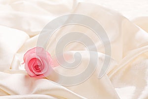 One pink rose laying in silk gift background